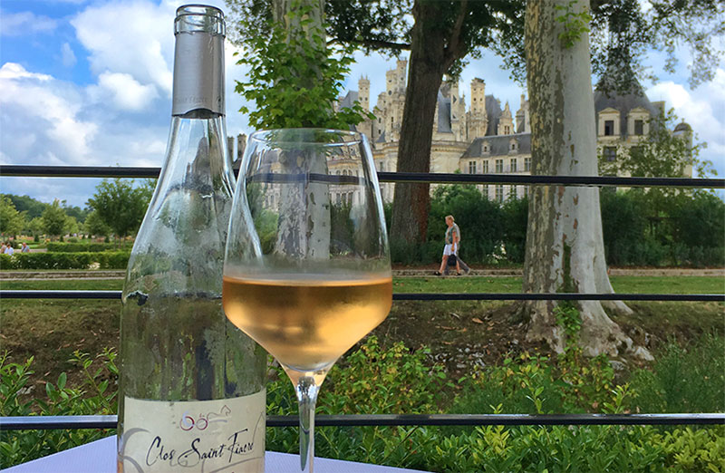 Botella de vino en una mesa de restaurante, Chateau de Chambord en segundo plano.