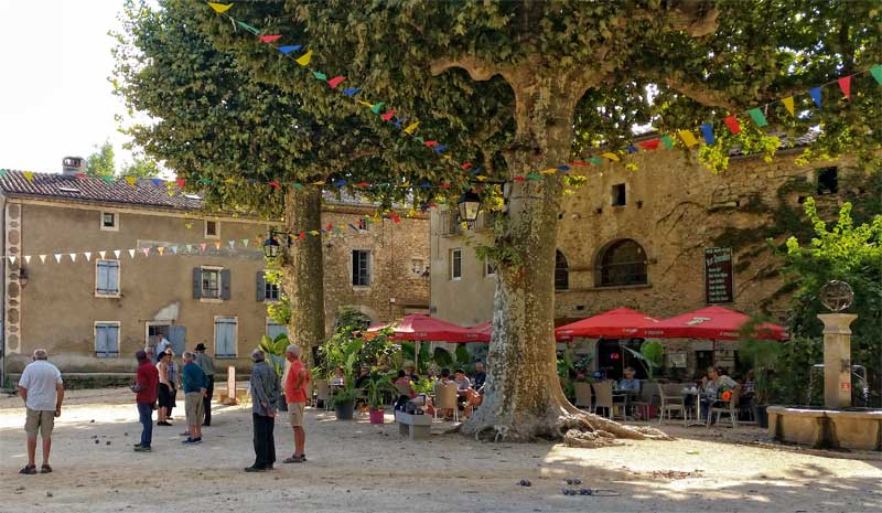 Gente jugando a la petanca, también conocida como petanca, en una plaza bajo los plátanos de Labaume Ardèche