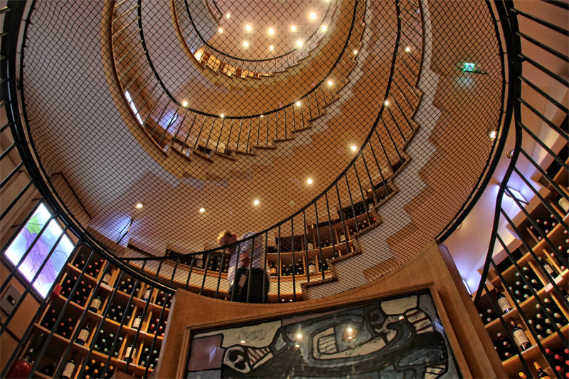 Una tienda de vinos en Burdeos con una escalera de caracol que sube cinco pisos y repleta de botelleros
