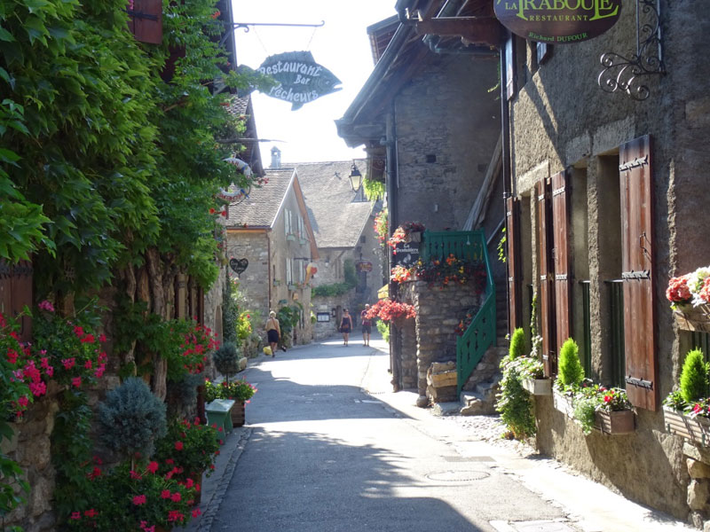 Calle colorida con flores en cajas en paredes, jardines y escaleras en Yvoire Alta Saboya