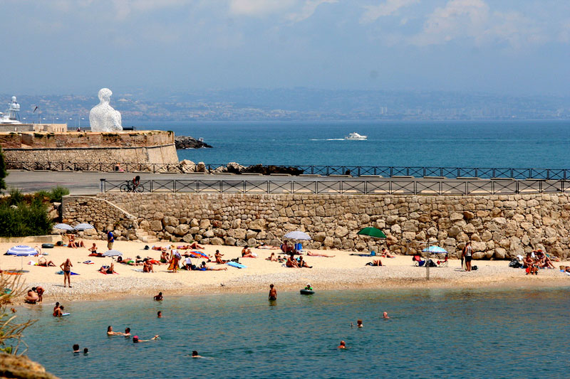 Gente tomando el sol en una playa de arena en un día soleado en Antibes, sur de Francia