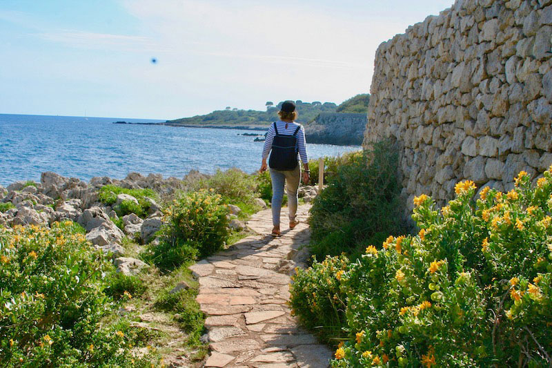 Mujer caminando por un sendero junto al mar Mediterráneo en Antibes, sur de Francia