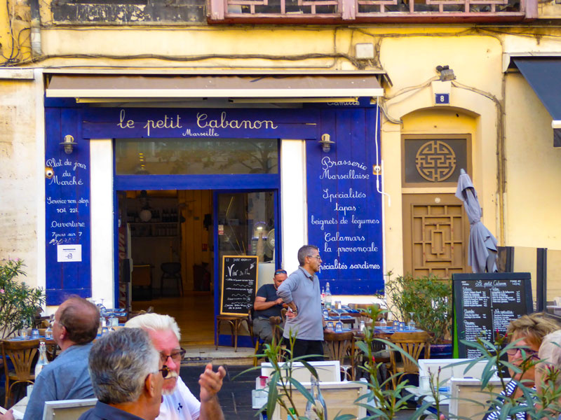 Bonito y pequeño café en Marsella, lleno de vida local bajo el sol. 