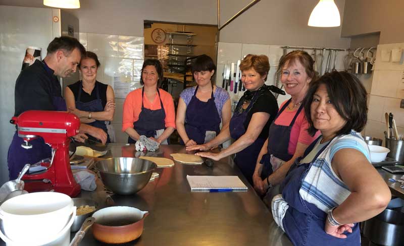 Grupo de mujeres disfrutando de una lección de cocina en la cocina de un chef en Provenza